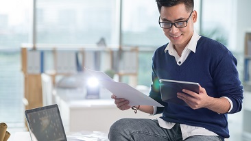 A guy looking at a tablet and a document